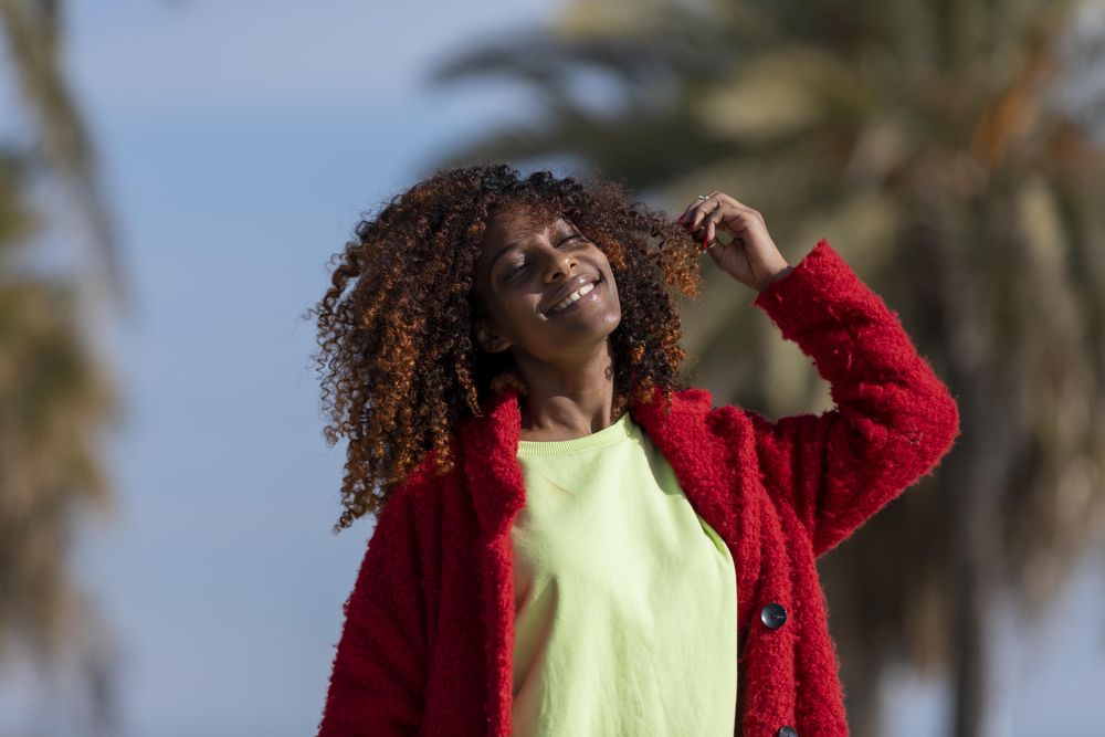 Female with curly hair smiling with the sunshine on her face