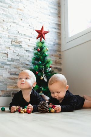 Twins on floor near Christmas tree