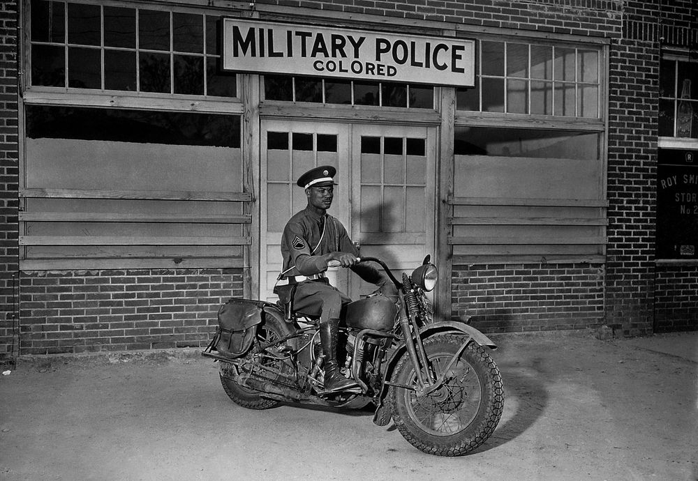 Black American soldier sitting on motorbike during World War II
