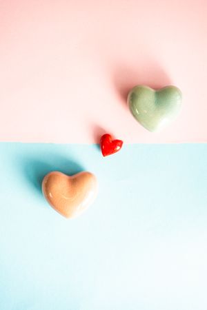 Orange, red and green heart ornaments on blue and pink pastel table