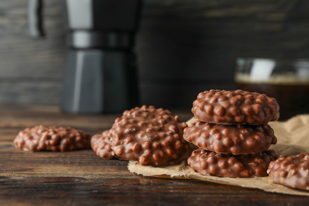 Chocolate cookies and cup of coffee on wooden table against dark background, space for text