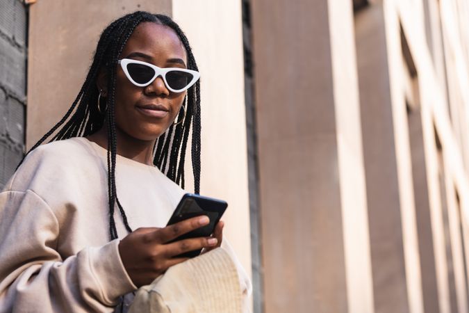 Black woman using smartphone near brick wall