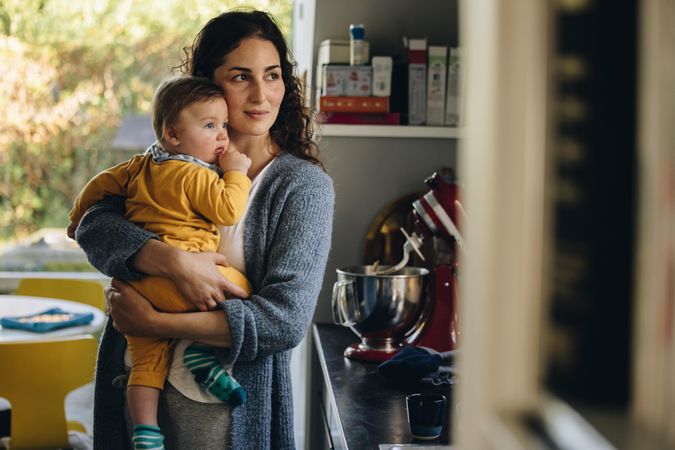 Mother and child together in kitchen looking outside window