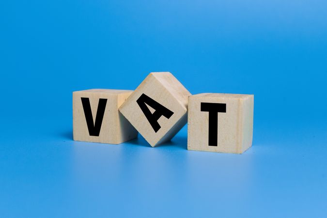 vat letter symbol or value added tax on wooden blocks isolated on blue background