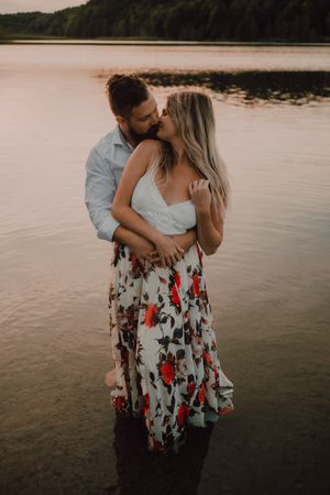 Loving couple hugging while standing ankle deep in water on beach