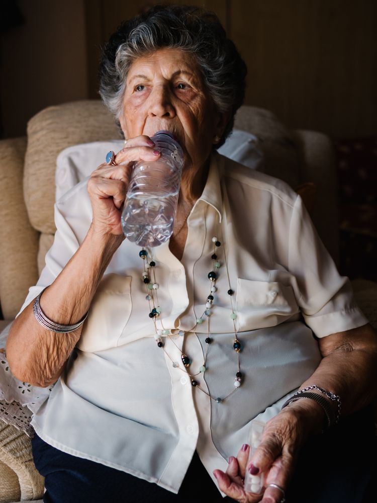 Mature female drinking medicines with water at home