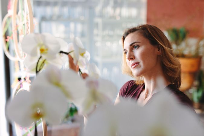 Woman admiring orchids in shop