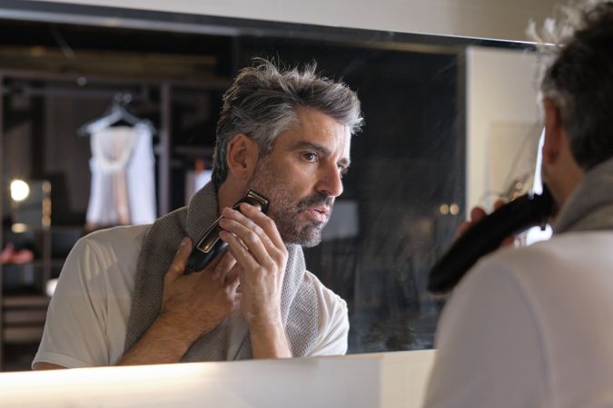 Mature male trimming beard in bathroom at home