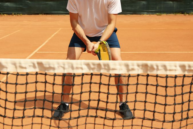 Young man playing tennis on clay court