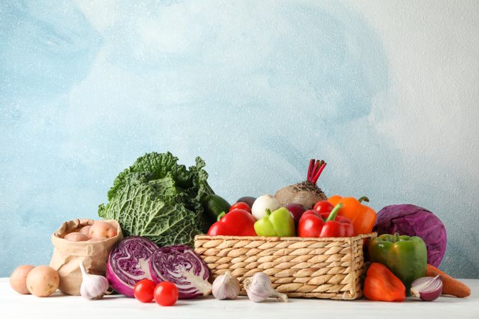 Wicker basket and vegetables on wooden background, copy space