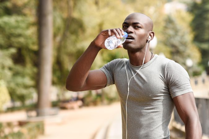 Healthy male drinking from a water bottle in an outdoor park