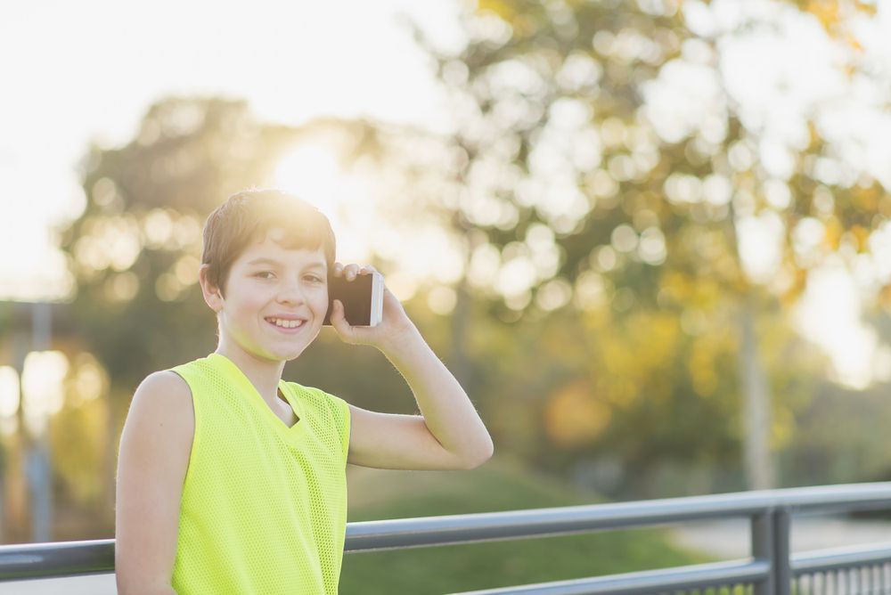 Portrait of a teenager smiling using his smartphone
