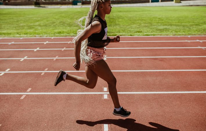 Black woman runner training on a running track