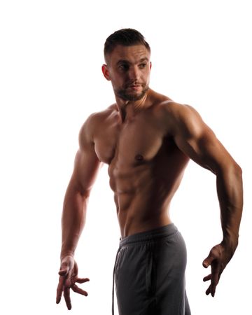 Bodybuilder looking around practicing side poses ahead of competition in bright studio