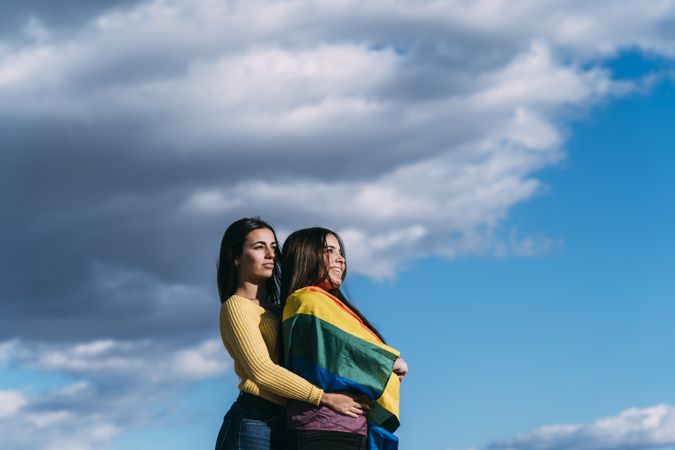 Young female couple with rainbow flag