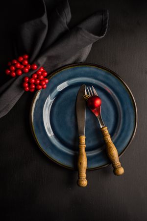 Navy plate on dark table with red decorative baubles and berries