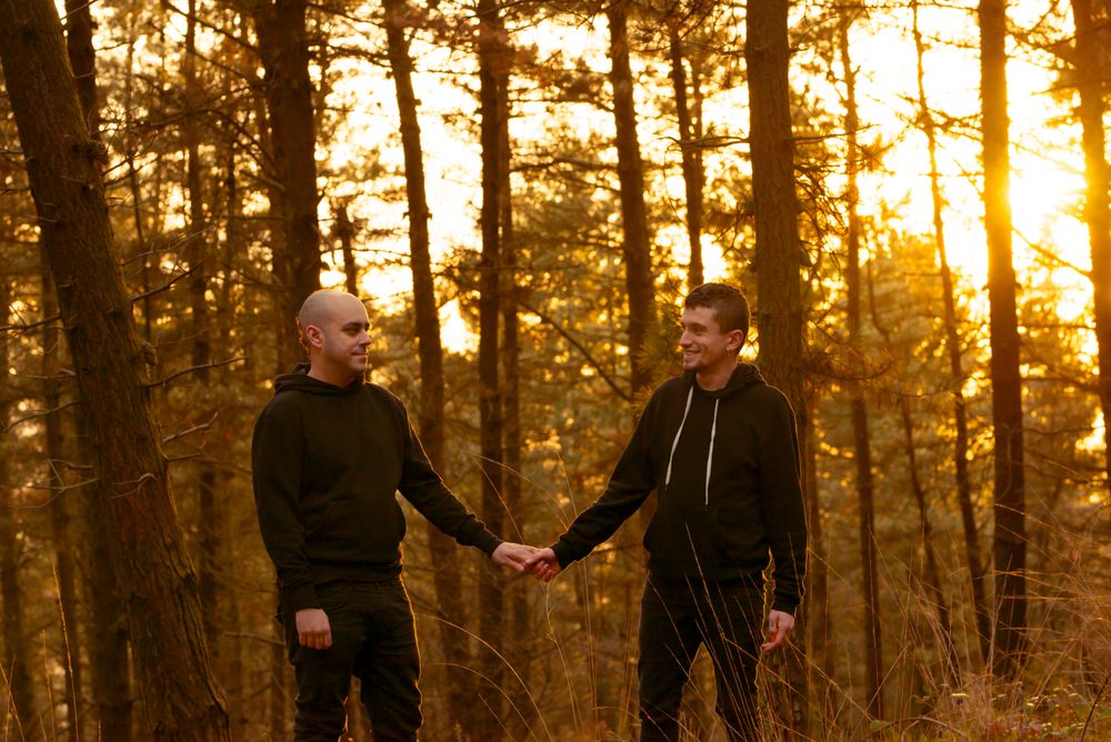 Men holding hands and walking in forest