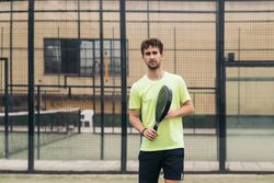 Young man playing paddle tennis on a green court