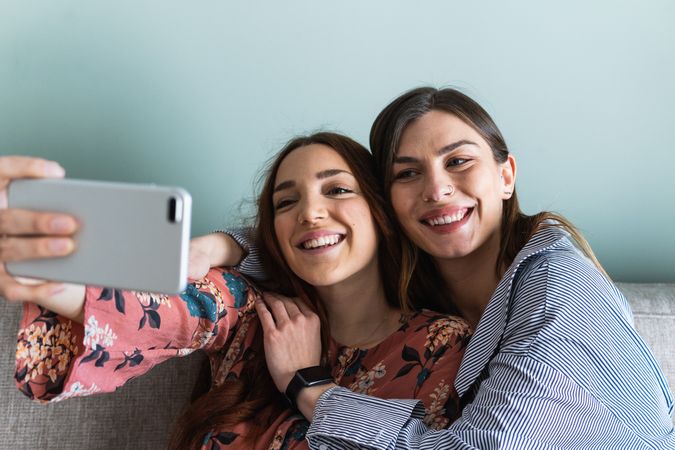 Smiling women hugging and taking selfie on smartphone