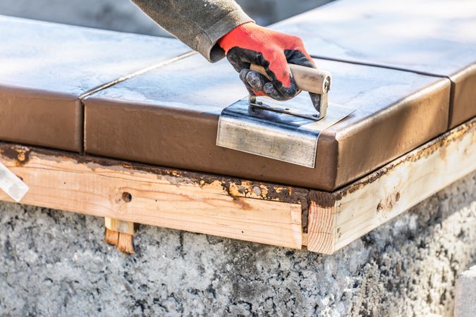 Construction Worker Using Stainless Steel Edger On Wet Cement Forming Coping Around New Pool