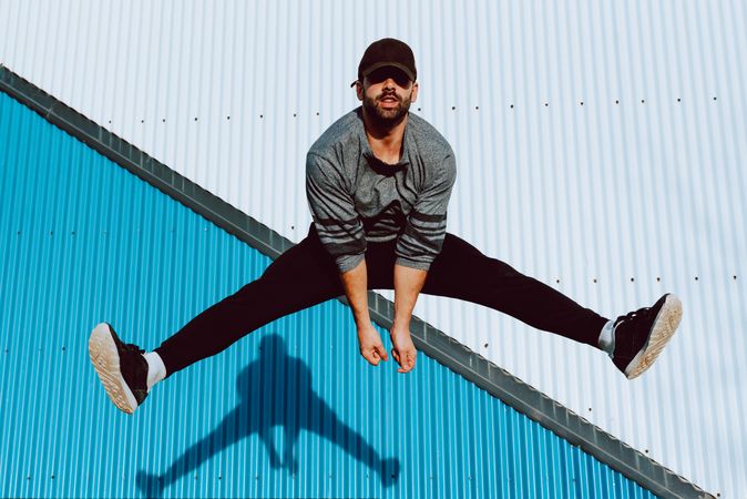 Trendy male flipping and jumping on street