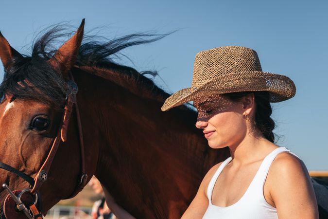 Woman taking care of his brown horse in an equestrian center