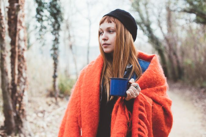 Woman wrapped in cozy blanket holding coffee