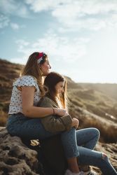 Young sisters sitting on stone on spring day
