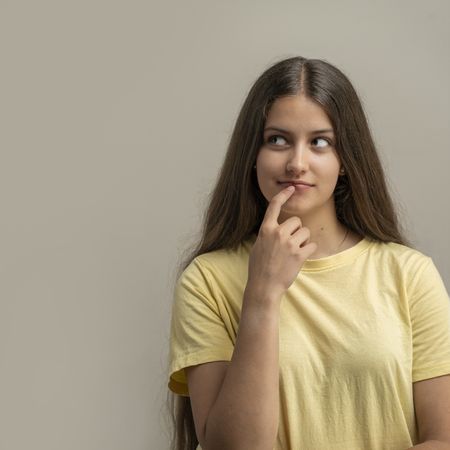 Thoughtful teenage girl with finger on lips natural skin texture confident expression