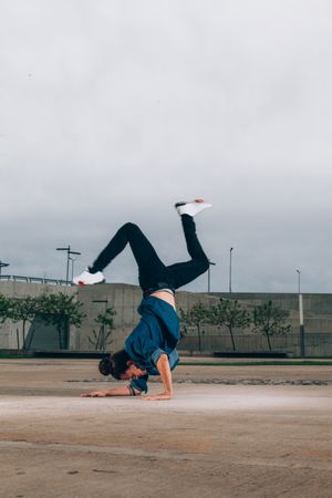 Skillful break dancer performing handstand while moving