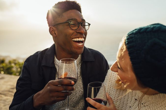 Cute couple drinking wine and laughing at outdoor picnic
