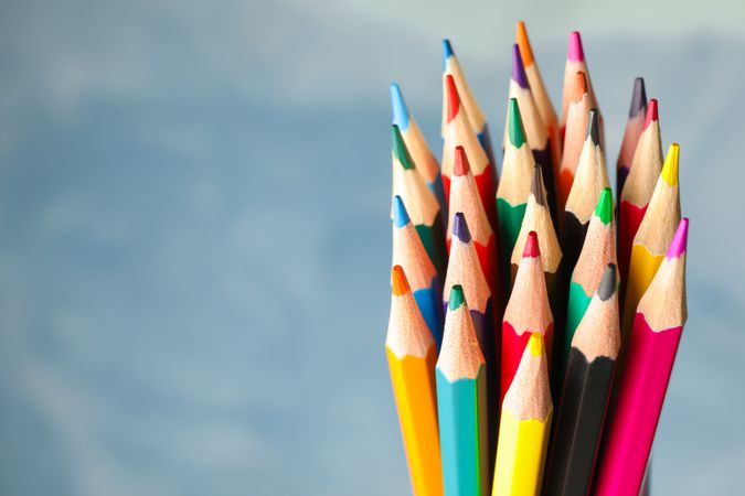 Multicolored pencils against light blue background, closeup