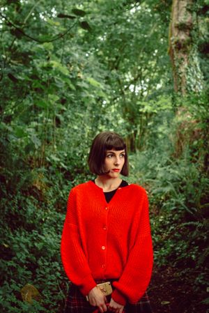 Woman in red with big red suitcase in forest
