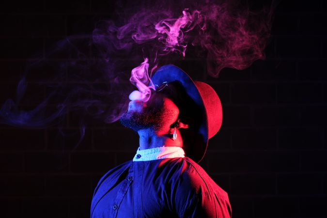 Serious man smoking on dark background