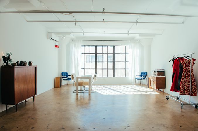 Wide shot of urban loft with large window and minimal furniture