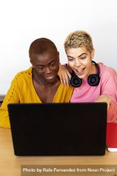 Female friends smiling at laptop bEGYV5