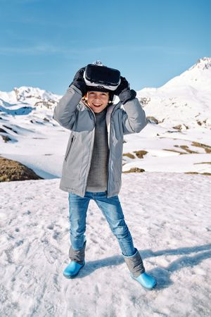 Excited boy in VR goggles in snowy countryside