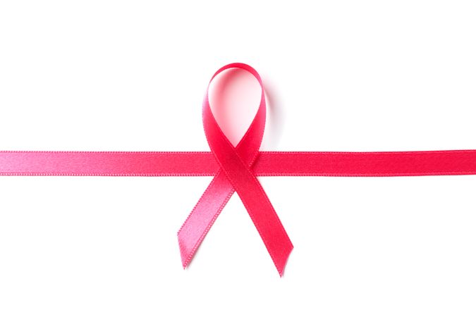 Pink awareness ribbon isolated on blank background, top view