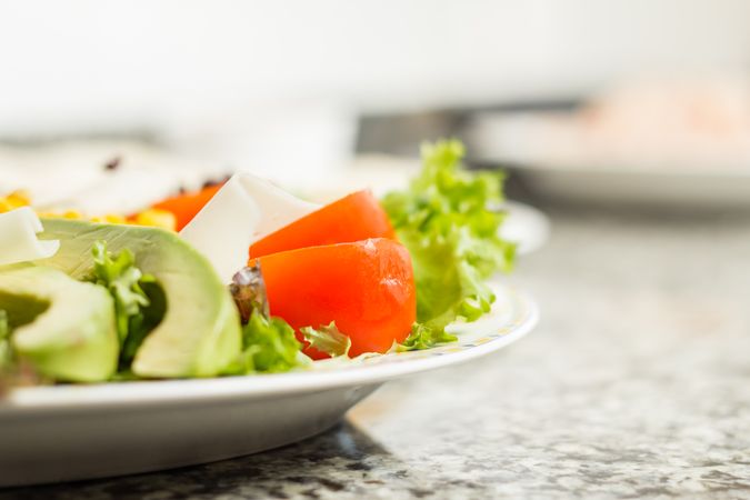 Closeup of salad with avocado, tomato, lettuce, cheese and corn