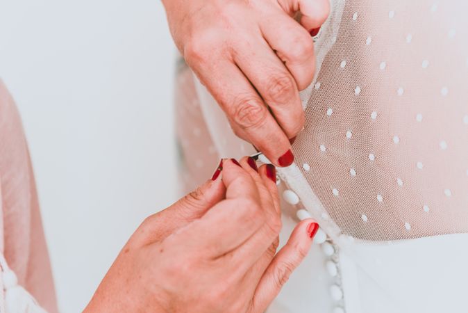 Woman buttoning up wedding dress on client