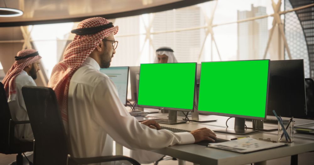 Arab Chief Financial Officer Working on Desktop Computer with Green Screen Mock Up Display.