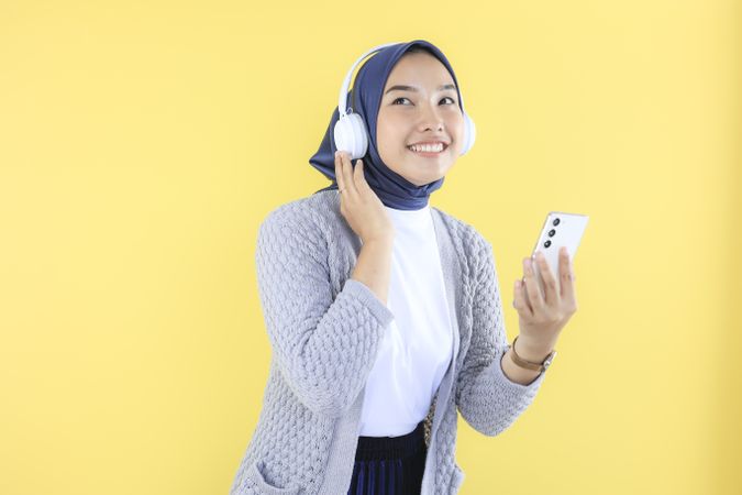 Young Asian Woman in Casual Shirt, Using Wireless Headphones for Listening to Music