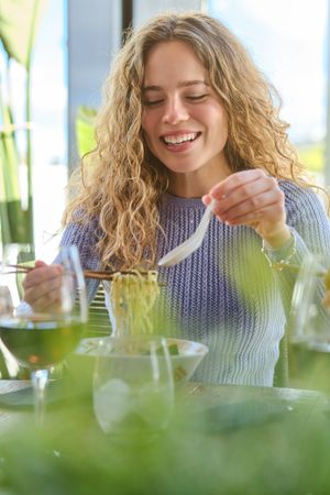 Smiling young female enjoying delicious ramen in modern restaura