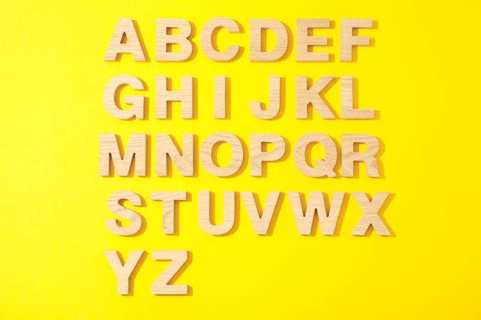 Wooden letters of English alphabet on color background, top view