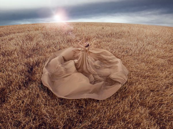 Top view of woman in big brown dress in wheat field