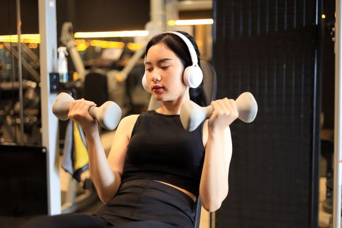 Asian Sport Woman Sit and Stay in Position of Exercise with Hold Dumbbells in Fitness Gym.