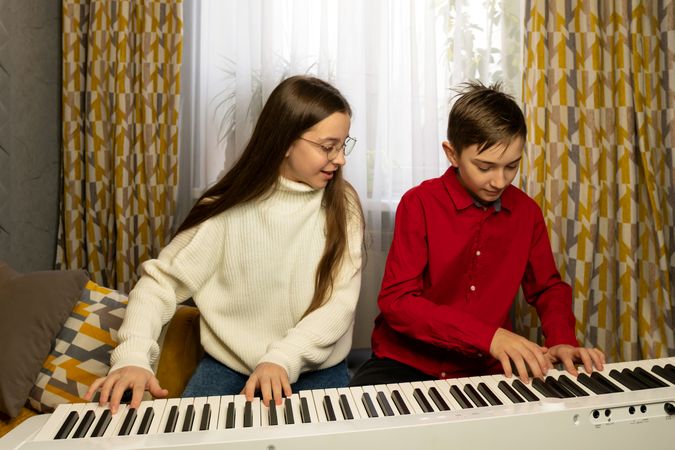 Two children playing the piano together