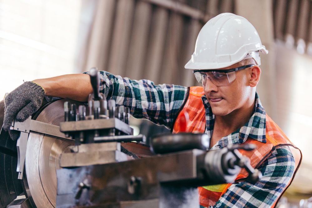 Confident male engineer metalworker with lathe machine