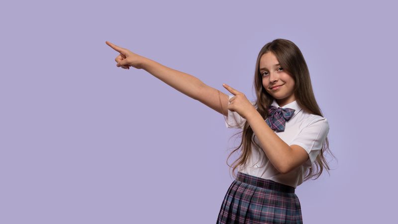 Young girl pointing upward with both hands.