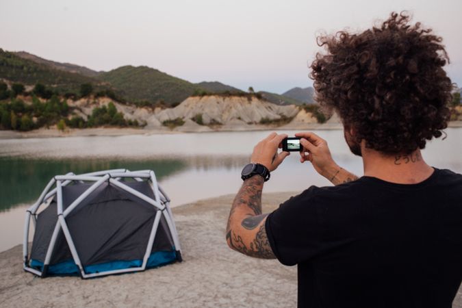 Rearshot of man taking picture of his camping site